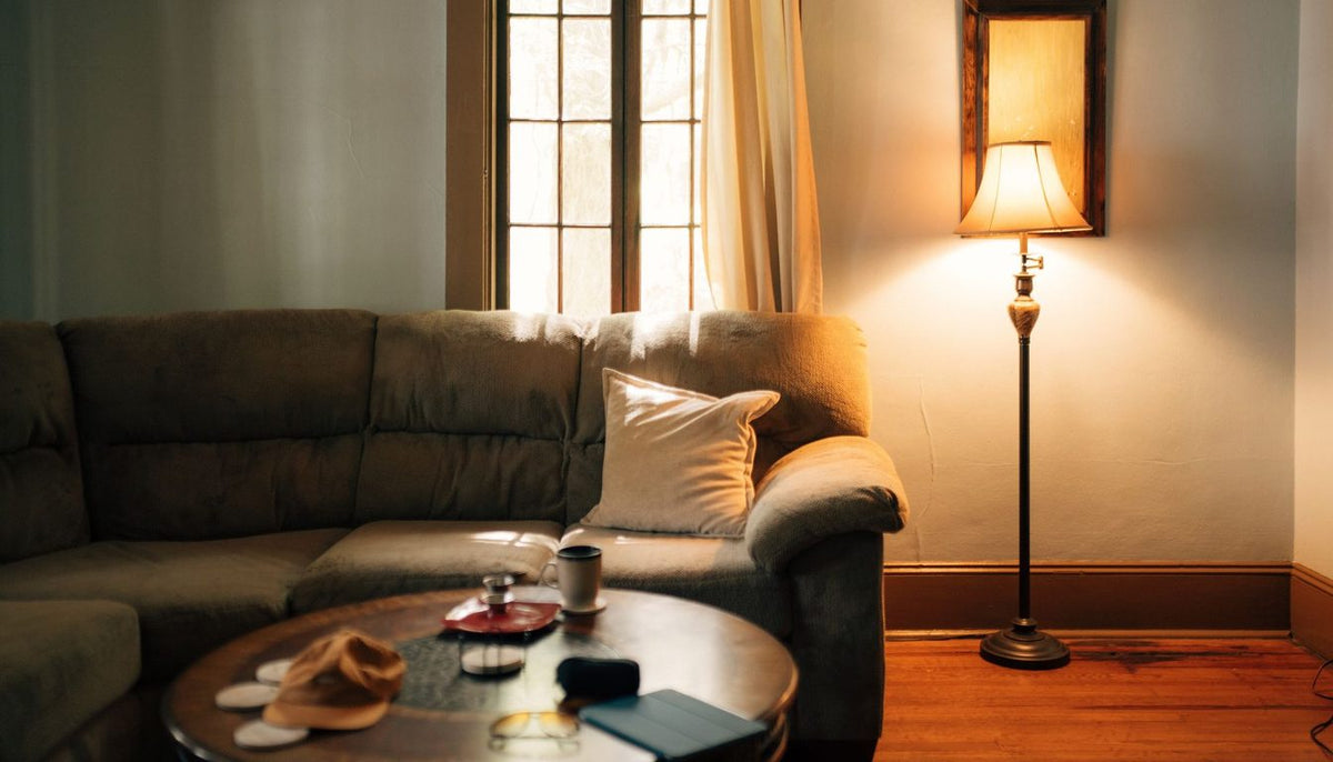 Salon chaleureux éclairé par une lampe, canapé beige et coussins dans des tons chauds Image